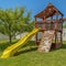 Square frame Wooden playground structure with yellow plastic slide swings and climbing wall