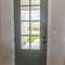 Square Front door with balck knob and glass panes against white wall and wood floor