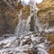 Square Frozen waterfall on a rugged and eroded cliff with trees and sky overhead