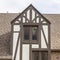 Square Gabled dormer with decorative windows against brick wall and roof of building