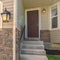 Square Garage door adjacent to concrete stairs that leads to the front door of a home