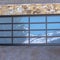 Square Garage door with glass panes reflecting a snowy hill landscape under blue sky