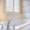 Square Gleaming built in bathtub and window with blinds inside a bathroom