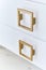 Square gold handles on a gloss cabinet doors of bathroom vanity