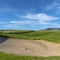 Square Golf course with sand bunker and vibrant fairway under blue sky on a sunny day