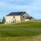 Square Grassy terrain and houses under blue sky with white clouds on a sunny day