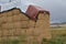 Square hay bales stacked and under protective tarpaulin