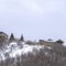 Square Hill with homes and leafless bushes on its gentle slope with snow in winter