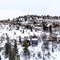 Square Hill top with family homes and abundant trees against overcast sky in winter