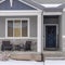 Square Home facade with gable roof front porch and door with wreath in winter