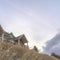 Square Home at neighborhood sitting on top of hill gainst snowy mountain and cloudy sky