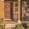 Square Home with pathway leading to gabled entrance of the front porch with brown door