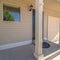 Square Home with small concrete porch in front of brown wooden door and shiny window