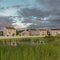 Square Homes with balconies and a view of grassy pond bridge and expansive green field