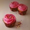 Square image of three cupcakes with pink frosting and colorful sprinkles with side lighting and vintage filter.