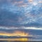 Square Lake and snow capped mountain underneath a sky filled with clouds at sunset