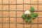 Square lined rope pattern on a wooden background and white rose with leaves interwoven between it. Texture for nature themes.