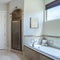 Square Master bathroom interior with antiqued limestone tiles