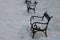 Square with metal benches in a row. The square is covered with snow and you can see the piles that the tractor pushed aside. The b