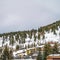 Square Mountain with colorful homes and coniferous trees on its snow covered slope