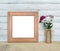 Square Old Wooden Frame mockup near a bouquet of sweet-william stands on a wooden table on a painted white wooden background.