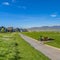 Square Pathway amid a rich green field leading to houses in the distance