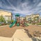 Square Pathway around childrens playground against townhomes and cloudy blue sky