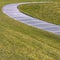 Square Paved footpath that curves through the grassy terrain viewed on a sunny day