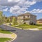 Square Paved road along lovely homes under blue sky with puffy clouds on a sunny day