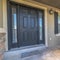 Square Pillars and railing on the porch of a home with gray front door and sidelights