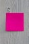 Square pink or red note paper with copy space is hanging on a gray wooden fence. Vertical