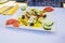 Square plate made of a Greek salad with feta, tomatoes, olives,