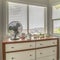 Square Potted cacti and electric fan on wooden cabinet against bay window of a home