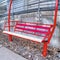 Square Red metal bench against building exterior with concrete wall and metal railing
