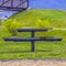 Square Round picnic table and seats on a lush field beside a road with brown grasses