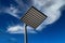 Square-shaped lamppost in the background of a cloudy sky with soaring birds