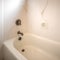 Square Shiny bathtub and shower inside the bathroom of a home with white wall