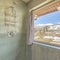 Square Shower room with large window with snowy grassy landscape and blue sky views