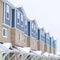 Square Snowy gable roofs at the facade of townhome with brick wall and vertical siding