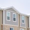 Square Snowy roof brick wall and vertical siding at exterior of townhome against sky