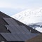 Square Solar panels installed on the dark roof of a home with snow in winter