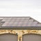 Square Solar panels installed on the garage roof of a home with cloudy sky background