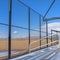 Square Sunlit bleachers overlooking a vast sports field on the other side of the fence