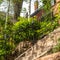 Square Sunlit stone stairway with black metal railing and brick house background