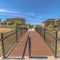 Square Sunny day view of bridge with brown deck and metal handrails over grassy terrain