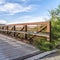 Square Sunny day view of a bridge with wooden deck and metal guardrail over a lake