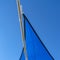 Square Thin triangular blue roof supported by smooth white poles against clear sky