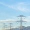 Square Towering power lines in the valley against snow capped mountain and blue sky