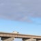 Square Truck travelling on a beam bridge over lake against rugged land and cloudy sky