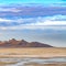 Square Vast sandy shore of a lake under bright blue sky with thick puffy clouds